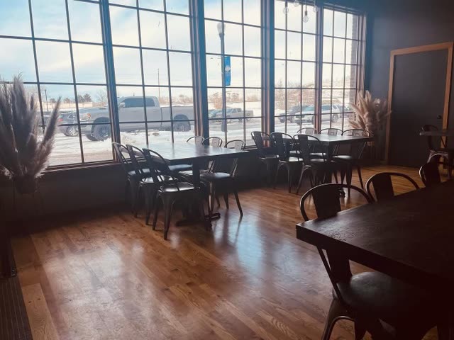 The dining room: dark wood tables, black metal chairs and tall windows full of winter sunlight